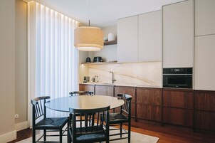 Una cocina moderna con una mesa de comedor redonda, armarios de madera oscura y un horno empotrado.