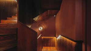 A wooden staircase with a circular light fixture at the top.