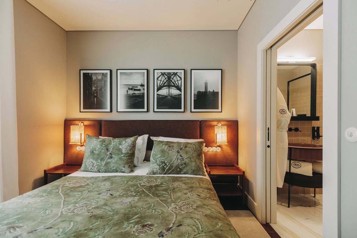 Een hotelkamer met een bed, twee nachtkastjes en een wand met drie ingelijste afbeeldingen.