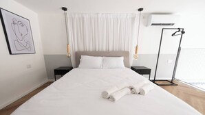 A hotel room with a large bed, two bedside tables, a hanging light fixture, and a framed artwork on the wall. - Port city haifa-Urbanic Loft heart of haifa Dwntwn (Haifa)