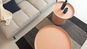A modern living room with a sofa, two round tables, and a patterned rug. - Port city haifa-Urbanic Loft heart of haifa Dwntwn (Haifa)