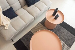 Ein modernes Wohnzimmer mit einer Couch, zwei runden Tischen und einem gemusterten Teppich.