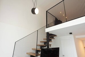 Un interior moderno con una escalera que tiene barandilla de metal negro y escalones de madera.