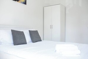 A hotel room with a bed, two pillows, a wardrobe, and a painting on the wall. - Port city haifa authentic 2bdrmsblcny germancolony (Haifa)