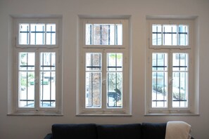 A room with three windows, a dark-colored sofa, and a white wall.