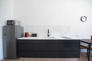 A modern kitchen with a built-in refrigerator, a microwave, a sink, and a coffee maker.