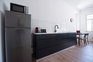 A modern kitchen with a stainless steel refrigerator, a black countertop, and a dining area with a table and chairs. - Port city haifa - authentic 2 bdrms germancolony 2 (Haifa)