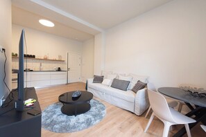 A modern living room with a sofa, a coffee table, a TV, and a dining area with a table and chairs. - Port city haifa - authentic 2 bdrms germancolony 3 (Haifa)
