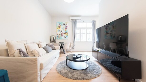 A modern living room with a sofa, coffee table, and TV. - Port city haifa - authentic 2 bdrms germancolony 3 (Haifa)