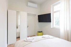 Una camera d'albergo con un letto, un armadio, una televisione e una finestra.