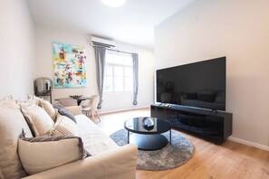 Un soggiorno moderno con un divano, un tavolino, una TV a schermo piatto e un quadro appeso al muro.