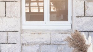 Ein Fenster mit weißem Rahmen und mehreren Glasscheiben, eingelassen in eine Steinwand.