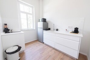 Une cuisine compacte avec des meubles blancs, un four à micro-ondes et un petit réfrigérateur.