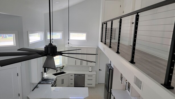 Eine moderne Küche mit Kochinsel, weißen Schränken und Deckenventilator.