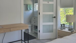 Ein Schlafzimmer mit Bett, Schreibtisch, Kleiderschrank und angrenzendem Badezimmer.