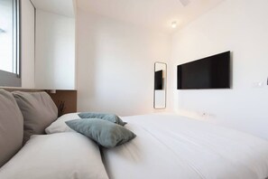 A modern bedroom with a bed, a bedside table, a mirror, and a wall-mounted TV. - Port city - Seaview Penthouse w/ Jaccuzzi + mamad (Haifa)