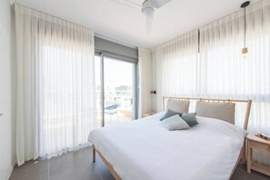 A modern hotel room with a large bed, a wooden headboard, and sheer curtains. - Port city haifa - SeaView 1 bdrm Penthouse (Haifa)