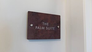 Ein Schild mit dem Schriftzug 'THE PALM SUITE' an einer Wand befestigt.