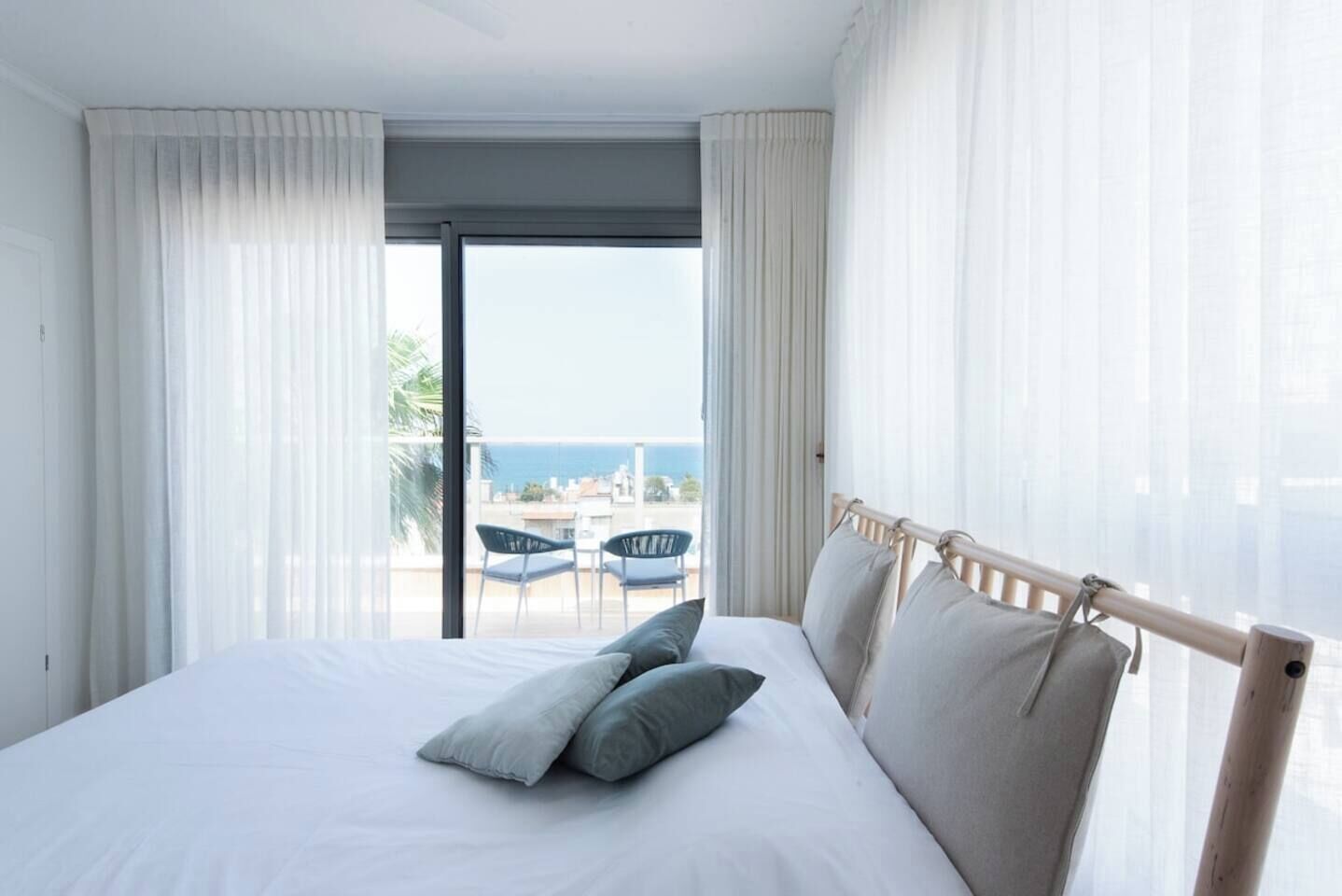 Habitación de hotel con cama, balcón con sillas y vista al mar.