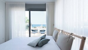 Ein Hotelzimmer mit Bett, einem Balkon mit Stühlen und Blick aufs Meer.