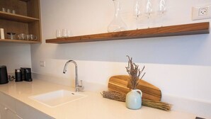 Eine Küche mit zwei Spülen, einer Kaffeemaschine und einer Vase mit Trockenpflanzen.