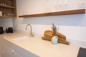 A kitchen with two sinks, a coffee maker, and a vase with dried plants. - Port city haifa - SeaView 1 bdrm Penthouse (Haifa)