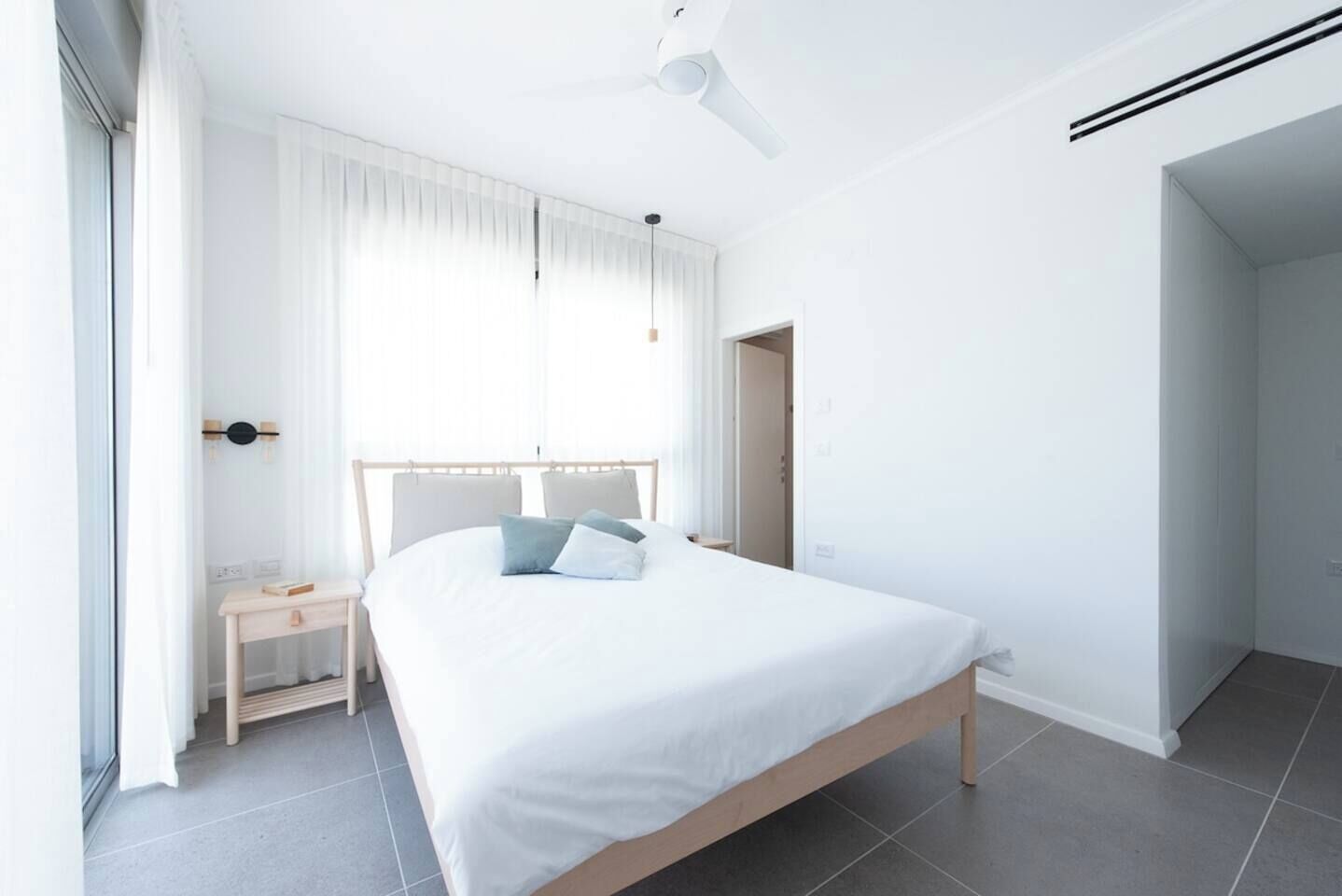 A bedroom with a bed, bedside table, and a window with curtains.