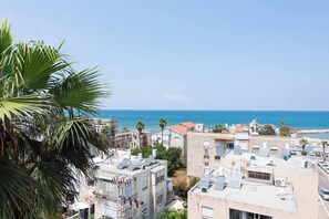 Uma área residencial costeira com edifícios, painéis solares e vista clara para o mar.