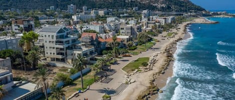 A coastal town with a beachfront, residential buildings, and a hilly backdrop.
