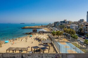Eine Küstenstadt mit sandigem Strand, einem Steg und Blick auf das Meer.