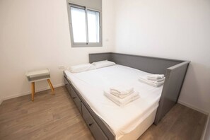 A bedroom with a bed, a bedside table, a window, and a radiator. - Port city - beach front Penthouse bat galim+mamad (Haifa)