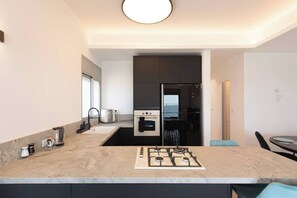 A modern kitchen with a gas stove, built-in oven, and a window overlooking the city. - Port city - beach front Penthouse bat galim+mamad (Haifa)