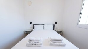 A hotel room with a large bed, two bedside tables, and a window.