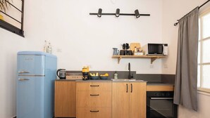 Una cocina compacta con un refrigerador azul, armarios de madera, un microondas y una cafetera.