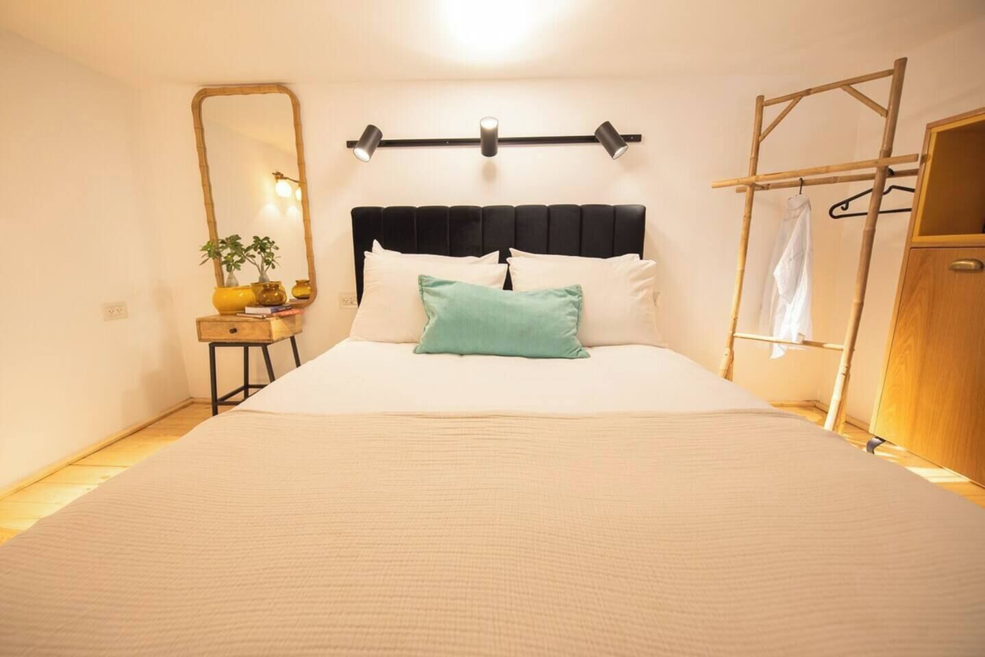 Una camera da letto con un letto, comodino, lampada, specchio e un armadio.