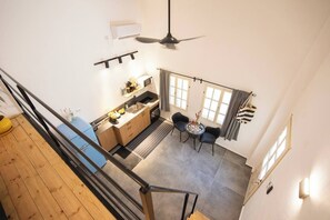 A kitchen with a dining area, a ceiling fan, and a window with curtains. - Port city haifa - Downtown Urban Oasis w Yard (Haifa)