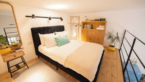 Un dormitorio con cama, mesita de noche, espejo, armario y una planta en maceta.