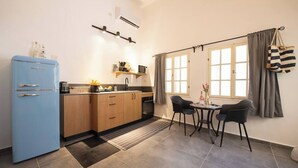 Una cocina compacta con un refrigerador azul, armarios de madera, un microondas y un pequeño comedor con dos sillas.