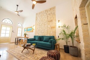 Un salon spacieux avec un canapé de couleur turquoise, une table basse et un mur d’accent en pierre.