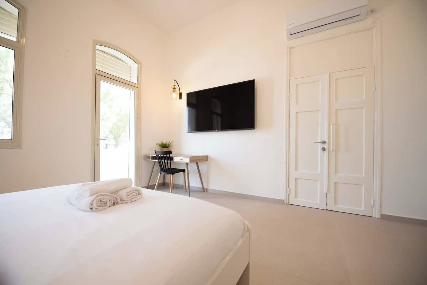 A bedroom with a bed, a desk, a chair, a TV, and a wardrobe.
