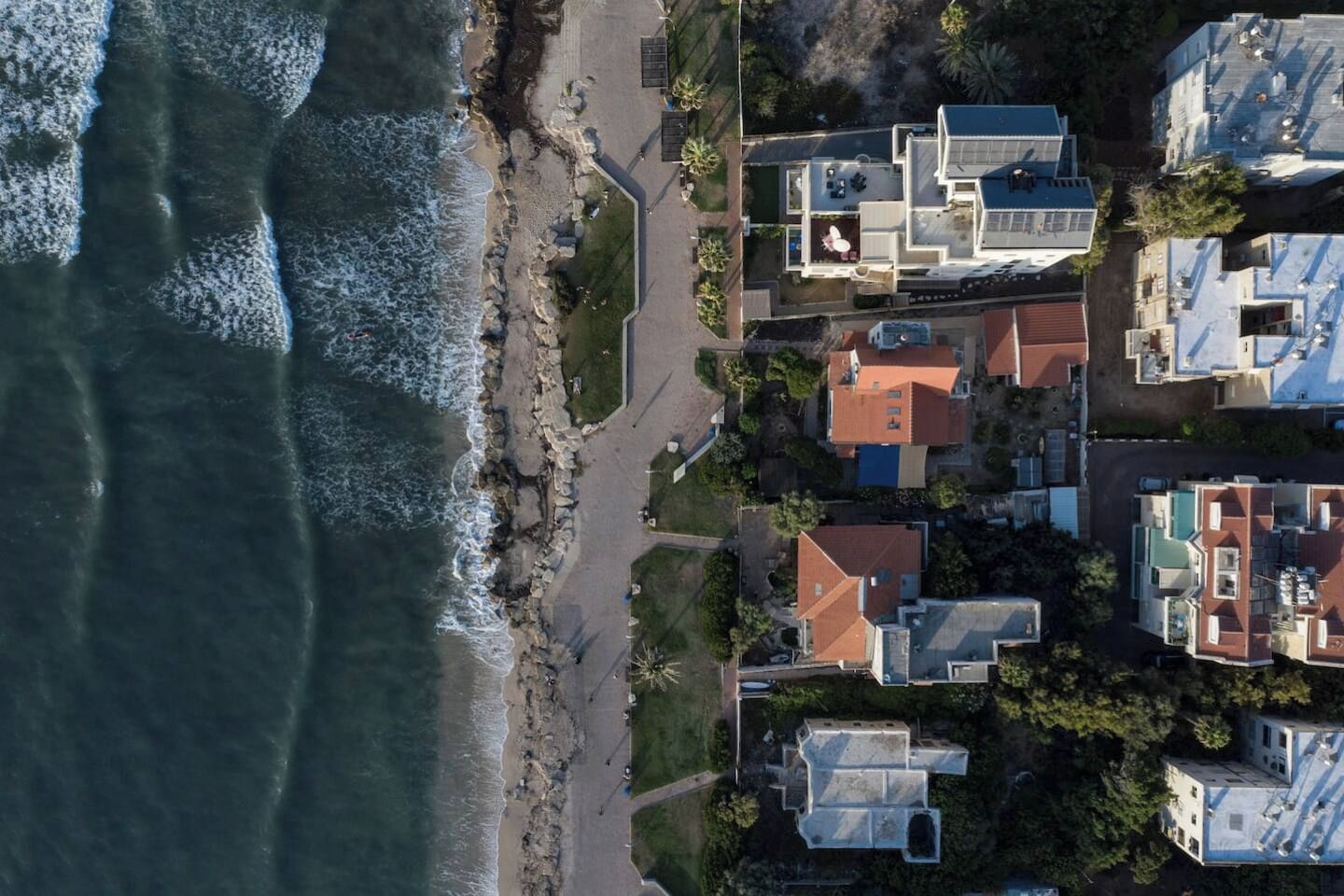Una zona residencial costera con casas junto a la playa, que presenta una combinación de edificios de uno y varios pisos.