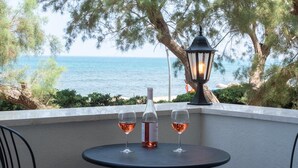 Une table avec une bouteille et deux verres de vin, une lanterne noire et une vue sur la mer.