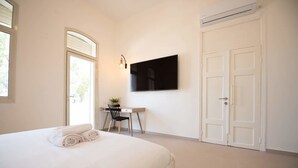 Une chambre à coucher comprenant un lit, un bureau, une chaise, une télévision et une armoire.