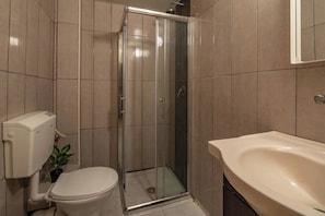Ein Badezimmer mit einer Duschkabine, einer Toilette und einem Waschbecken.