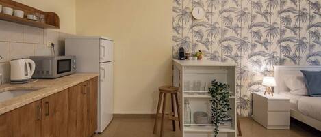 Un espacio habitable compacto con kitchenette, una pequeña zona de comedor y un dormitorio.
