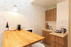 Eine kleine Küche mit einer Holztischplatte, einem weißen Toaster, einem Wasserkocher und einer Kaffeemaschine.