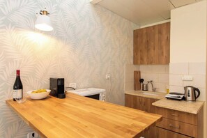 Eine Küche mit Holztischplatte, einer Weinflasche, einer Schüssel, einer Kaffeemaschine und einem Wasserkocher.