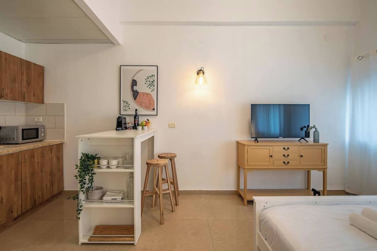 Habitación compacta con kitchenette, cama, TV y una pequeña zona de estar.