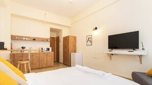 Quarto de hotel com cama, televisão, cozinha compacta e banheiro.