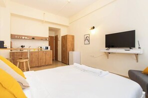 Ein Hotelzimmer mit Bett, Fernseher, Küchenzeile und Badezimmer.